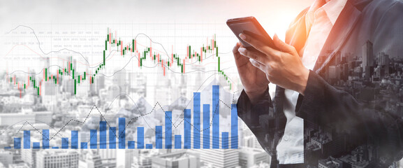 A business professional examines stock market data and trends on a smartphone while standing...
