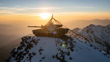 Tank on snowy mountain peak with prayer flags against sunrise. Military might above mountains.