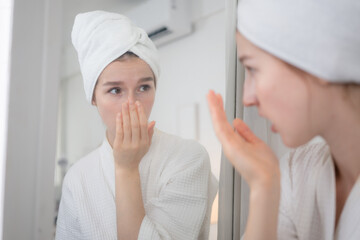A young woman stands in front of a mirror, brushing her teeth