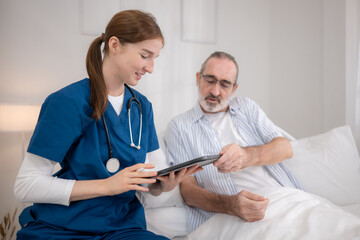 Obraz premium Female nurse assisting an elderly patient in bed while reviewing medical information