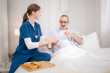 Obraz premium A female nurse assists an elderly patient in bed with food and medication before meals