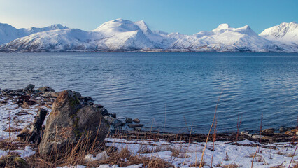 Snow-covered mountains and blue fjord in Arctic Tromsø, Norway