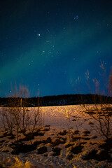 Snow field with northern light in night sky.