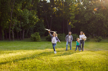 Happy family spending summer time holiday together outdoors in green park, interacting with...