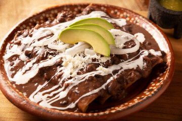 Enfrijoladas. Corn tortillas bathed in bean sauce, covered with cream and cheese, they can be covered or filled with chicken meat, chorizo, cheese or some other ingredient. Traditional Mexican dish.