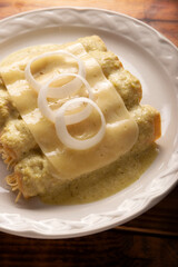 Green Enchiladas with creamy green sauce filled with shredded chicken meat and covered with melted cheese, in Mexico they are called Swiss Enchiladas. Very popular recipe in Mexican cuisine.