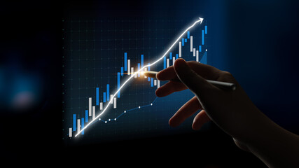A hand points to a digital graph showcasing a stock market trend with an upward trajectory. This...
