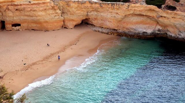 A top down high angle view of a single unrecognisable figure fishing in an idyllic Algarve cove in Portugal