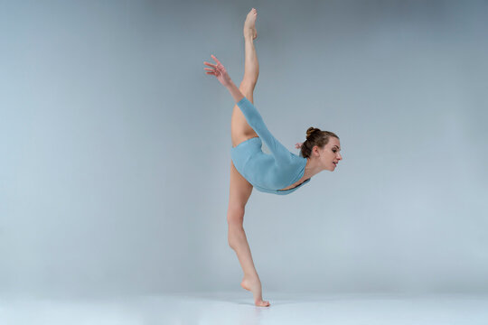 ballerina with beautiful feet poses in a photo studio, shows vertical splits in leotard and pointe shoes