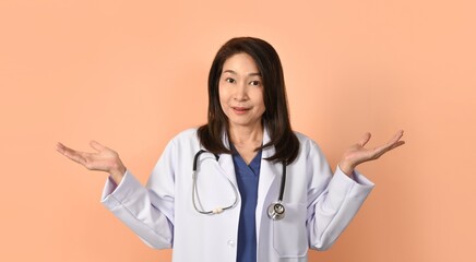 Portrait of asian female doctor in medical uniform with stethoscope on peach color background.
