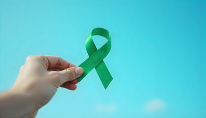 A hand showcases a green ribbon against a blue sky, symbolizing Glaucoma Awareness and the fight against vision loss