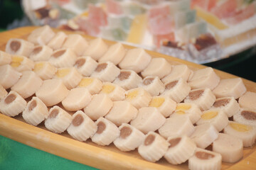 Colorful candies displayed on a wooden tray at a market