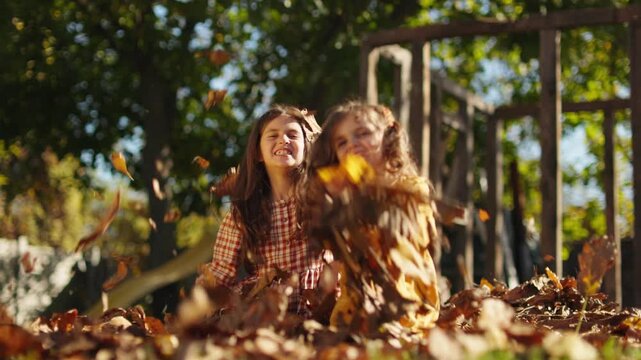 Happy little girls playing in autumn leaves