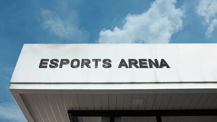 Esports Arena word sign prominently displayed on the modern entertainment building facade beneath a clear blue sky, signifying a dedicated venue for competitive video gaming events and spectators.