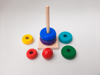 Wooden stacking toy pyramid with colorful rings arranged on a vertical peg.