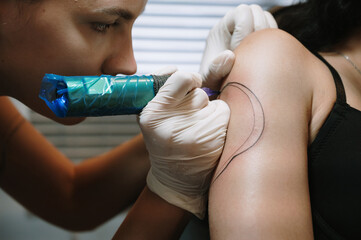 Close-up of a female tattoo artist getting a tattoo in a studio getting a tattoo on a woman's body.