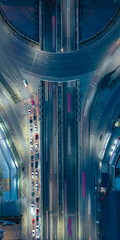 Aerial view of city highway interchange at night with light trails from moving cars, showing modern urban infrastructure and transportation network.