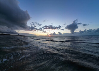 A tranquil ocean scene beautifully capturing a stunning sunset set against a backdrop of dramatic clouds