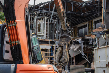 グラップルアタッチメントを付けた重機で解体工事をしている