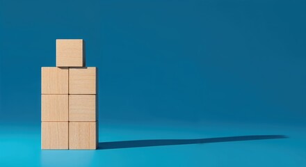Obraz premium Human Formed by Blocks: Minimalist shot of a human figure meticulously constructed from wooden blocks, cast in a deep blue backdrop creating a play of light and shadow, representing concept.