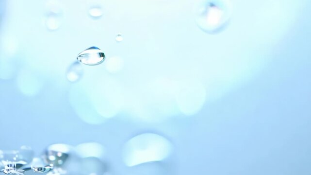 Clear water droplets descend through air hitting surface and bouncing back in slow motion showing purity freshness and dynamic movement in bright blue background