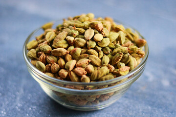 Fragrant cardamom in a glass bowl on a blue background