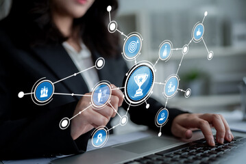 A professional businesswoman interacts with digital achievement symbols and a network interface while using her laptop, highlighting modern work dynamics and success. Crux