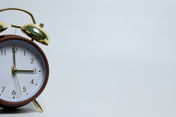 Vintage alarm clock standing on a clean white background with minimalist lighting. Classic...