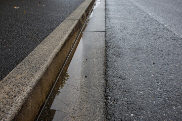 雨上がりの道路のL字側溝に水が溜まっている