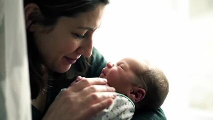 Mother tenderly gazing at newborn in window light, symbol of nurturing and unconditional love