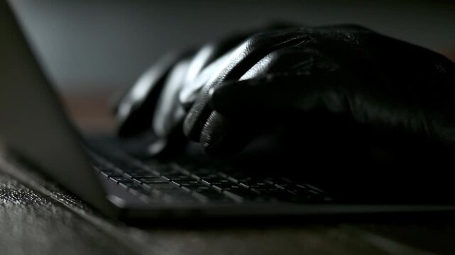 Hacker's gloved hands on laptop keyboard. High quality FullHD footage