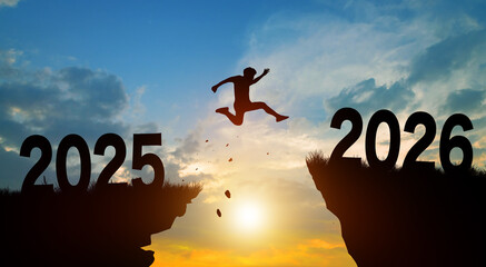 Happy new year in 2026. Man jumping across the gap from 2025 to 2026 cliff with Sunset and Twilight Sky background.
