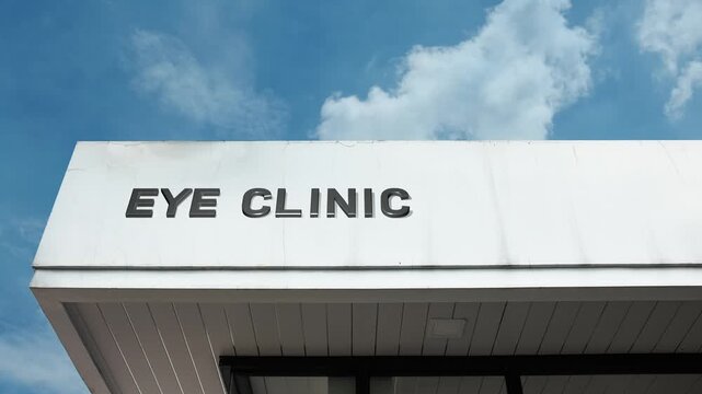 Eye Clinic word sign clearly displayed on the medical facility facade beneath a clear blue sky, signifying a healthcare center specializing in vision care, ophthalmology, and optometry services.