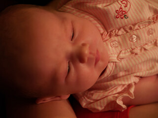 Tight Shot Of Young Infant Baby Girl With Eyes Nearly Closed