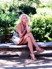 Blond Caucasian Woman Sitting Outdoors On Cement Bench