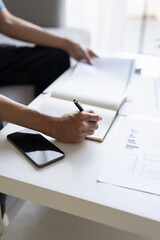 Asian Man Taking Notes on Finances, Budget, Household Expenses, and Tax Calculations in Notebook at...