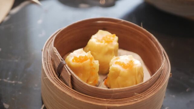 close up view to a steamer full with suimai dimsum in hongkong style while using chopstick to pick up dimsum to eat,chinese dimsum food eating