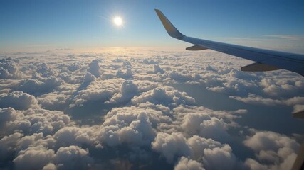View from an airplane window above the clouds showing the aircraft wing during a high-altitude flight - Powered by Adobe