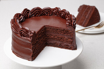 Chocolate cake on a stand with slice on plate 