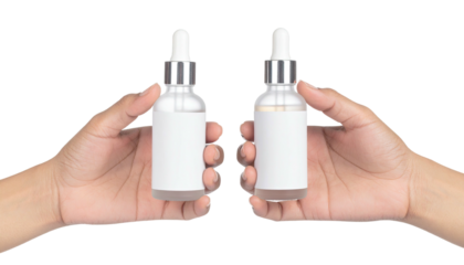 Hands hold two small bottles with droppers. Isolated
