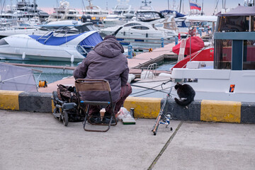 Fisherman together with cat in the Sochi port water area Sochi. Krasnodar Krai, Russia