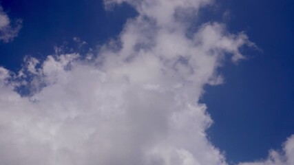 Real-time footage of white clouds drifting across blue sky