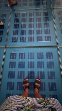 personal perspective, woman standing on solar panel glass floor with lights and people walking around in Zadar, Croatia