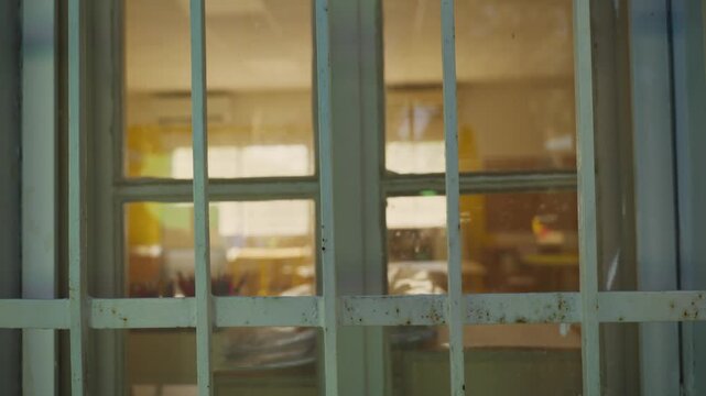 School window, looking into an empty classroom. Slow dolly-in move toward window. Calm, vacant scene education, school closure, safety, lockdowns, truancy, or investigations. No people. sad, lonely