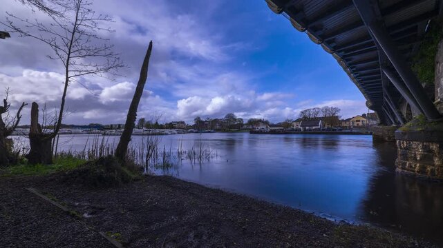 Timelapse of Carrick on Shannon town bridge in county Leitrim and Roscommon with river Shannon in the foreground and traffic, people and fast moving daytime clouds in Ireland.