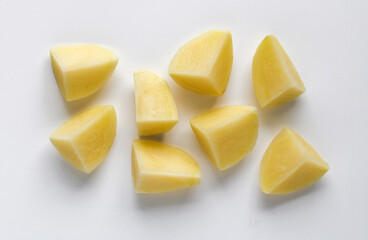 Several chunks of raw potato arranged on a white background, showing the smooth texture and yellow flesh.