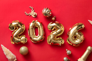 Figure 2025 made of foil balloons with Christmas decorations and bottle of champagne on red background