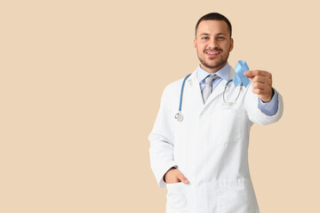 Male urologist with blue ribbon on beige background. Prostate cancer awareness concept
