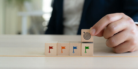 Goal setting and achievement concept. Step by step success strategy. Wooden blocks with flag and target icon. Progress tracking, goal setting and achievement in business or personal development.