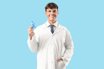 Male doctor with blue ribbon on color background. Prostate cancer awareness concept